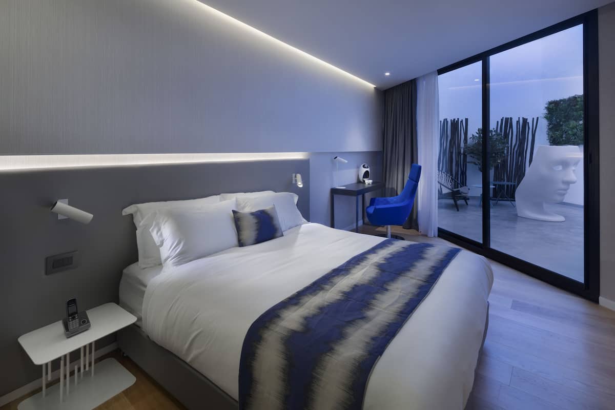 Ein modernes Hotelzimmer mit einem großen Bett, einem Nachttisch und Blick ins Freie.