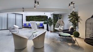 Ein modernes Interieur mit einer Sitzecke, die eine Couch und Sessel, einen Hängekorbstuhl und eine Vogelkäfig enthält.