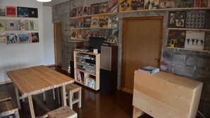 A room with a wooden table, a bookshelf, and a wall decorated with album covers. - Guest house ISA (Motobu)