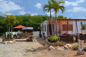 Una casa móvil con mobiliario exterior, rodeada de plantas en macetas y un camino de grava.