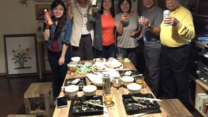 A group of people at a dining table with various dishes, drinks, and a bottle of wine. - Guest house ISA (Motobu)