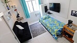 A compact hotel room with a bed, a sofa, a TV, a coffee maker, and a small table. - Rio Spot Apartment C019 (Rio de Janeiro)