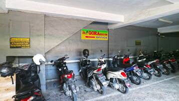 A row of motorcycles parked in a covered area with a sign indicating the GORA BEACH INN Office.