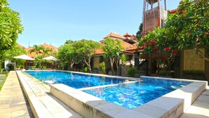 A rectangular swimming pool with a tiled edge, surrounded by a stone deck. - Gora Beach Inn (Kuta)