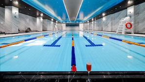A large indoor swimming pool with clear lane markings, a lifebuoy, and a glass of red drink on the edge. - Shanghai Donghu Hotel (Shanghai)