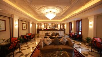 A spacious lobby with a central seating area, a bar, and a chandelier.
