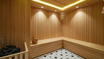 Una sauna amb parets i bancs de fusta, un terra d'rajola i un cubell de fusta.