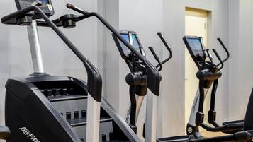 A row of stationary bikes with digital displays, arranged in a gym setting.