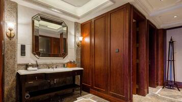 Un baño lujoso con tocador de mármol, un espejo grande y paneles de madera.