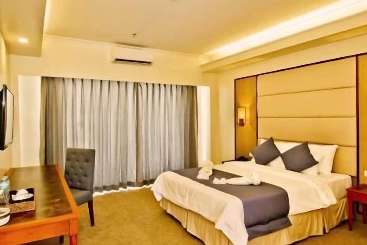 Una habitación de hotel con una cama, un escritorio, una silla y un televisor.