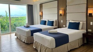 Habitación de hotel con dos camas, un ventanal con vistas a zonas verdes y aire acondicionado en el techo.