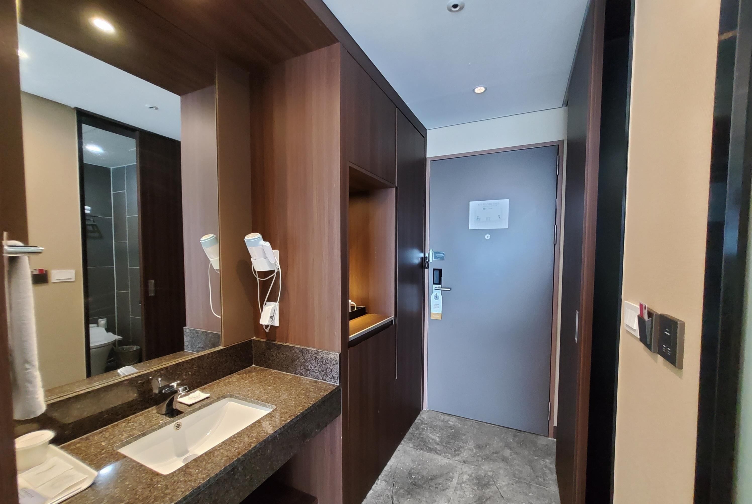 A modern bathroom with a granite countertop sink, a large mirror, and a shower area.
