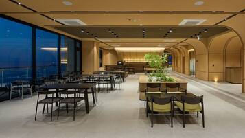 A spacious dining area with high ceilings, large windows, and a central plant feature.