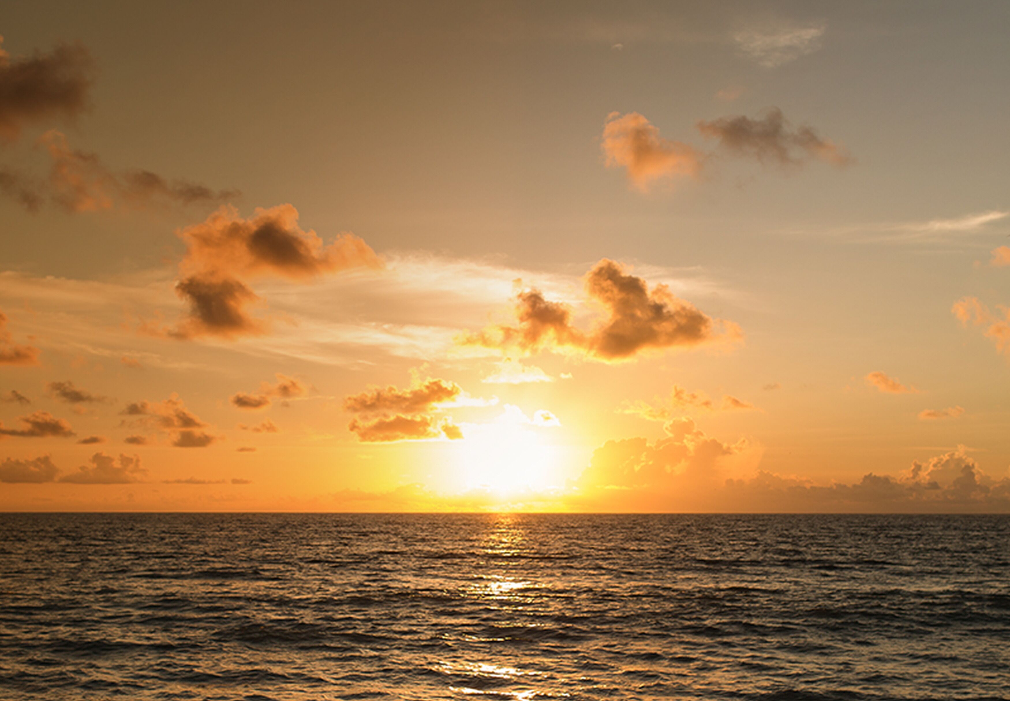 Ein Sonnenuntergang über dem Meer mit Wolken am Himmel.