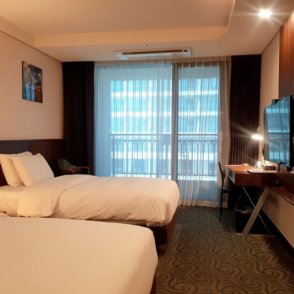 A hotel room with two beds, a desk, a chair, a TV, and a balcony with a view. - Ramada Sokcho Hotel (Sokcho)