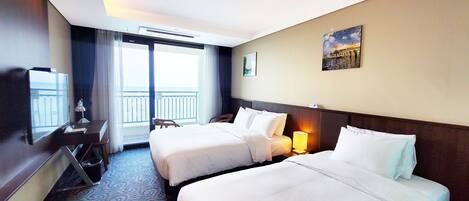 A hotel room with two beds, a desk with a chair, a television, and a window with a view of the outside.