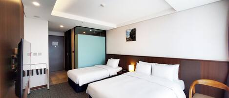 A hotel room with two beds, a desk, a chair, and a wardrobe.