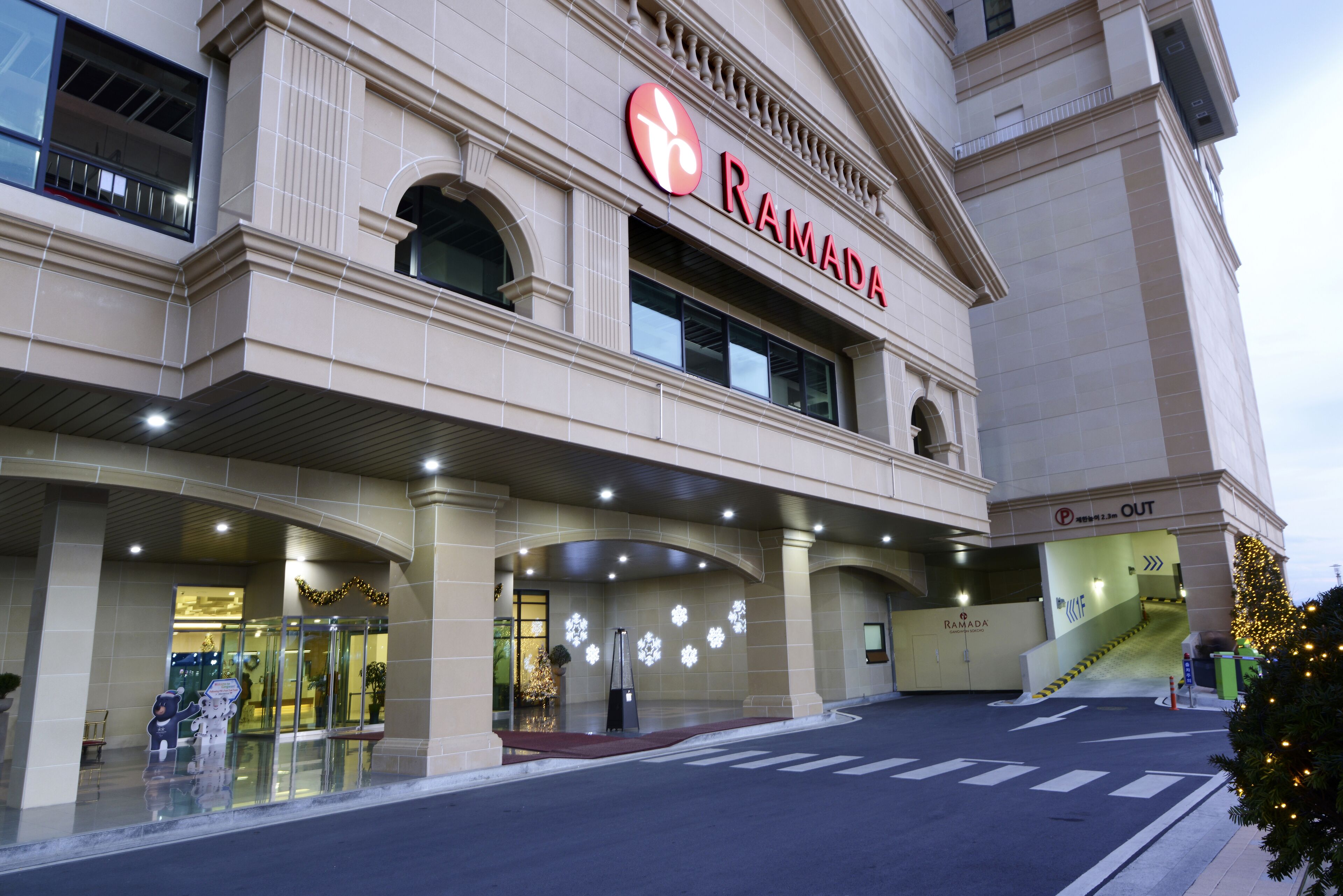 A building with a "RAMADA" sign, a covered entrance, and a staircase leading to an upper level.