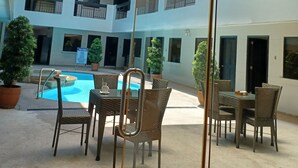 Une cour intérieure à plusieurs niveaux, avec une piscine, des espaces de détente en plein air et des plantes en pot.