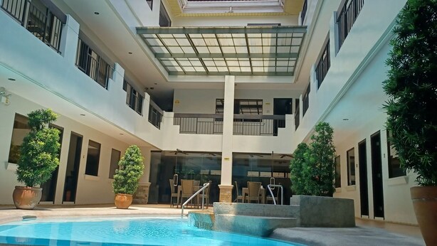 Un atrium à plusieurs niveaux, doté d’une piscine centrale, de plantes en pot et d’un plafond en verre.