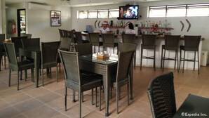 Un restaurant avec des chaises en osier, un coin bar et des ventilateurs de plafond.
