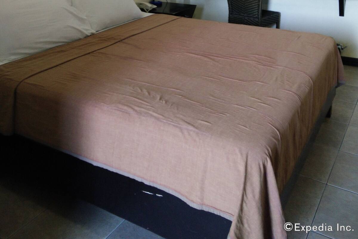 Een hotelkamer met een bed, een bureau, een stoel, een plafondventilator en een raam.