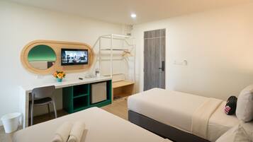 A hotel room with a bed, a desk with a computer, a TV, a wardrobe, and a bathroom.