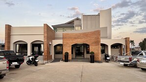 A modern building with a flat roof, multiple entryways, and a parking area with vehicles. - KYP Hotel (Fang)
