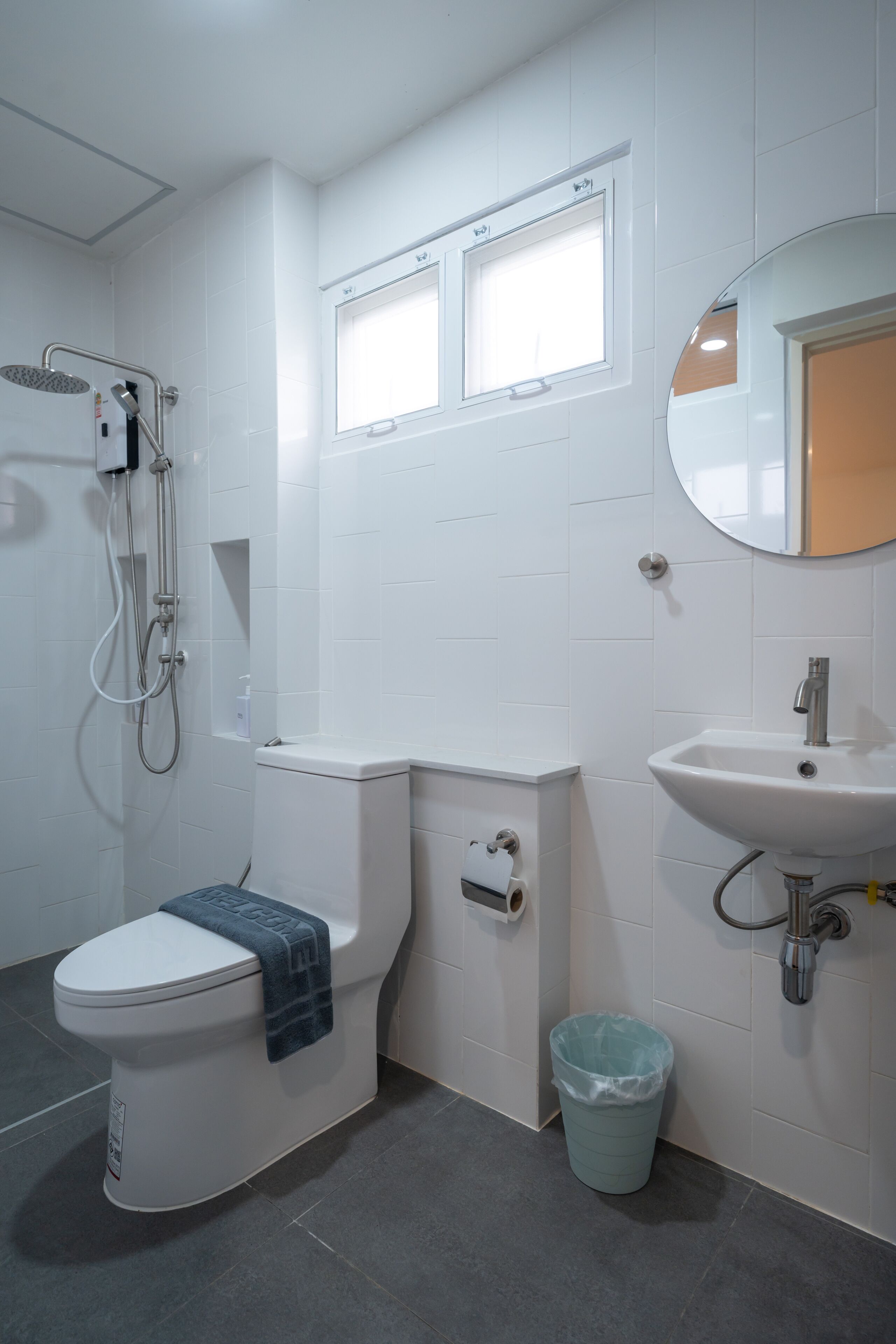 Une salle de bain comprenant des toilettes, un bidet, une douche, un lavabo et une poubelle.