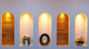 Una pared con cuatro nichos de arco, cada uno con un reloj y un arreglo floral.