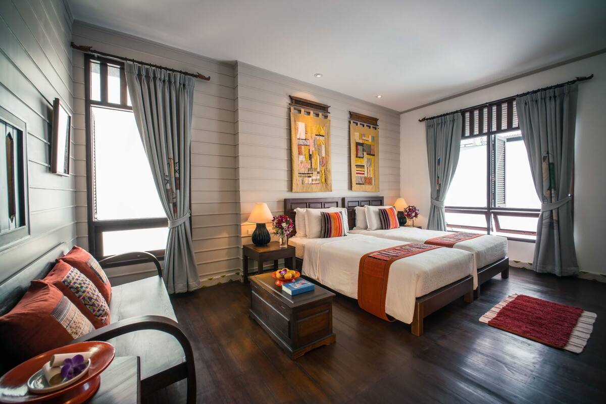 A hotel room with a large bed, two bedside tables, a desk, and a chair.