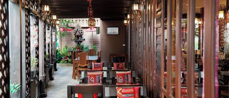 Stroll through a warm and inviting corridor lined with lattice partitions, framed artwork, and cozy seating areas.