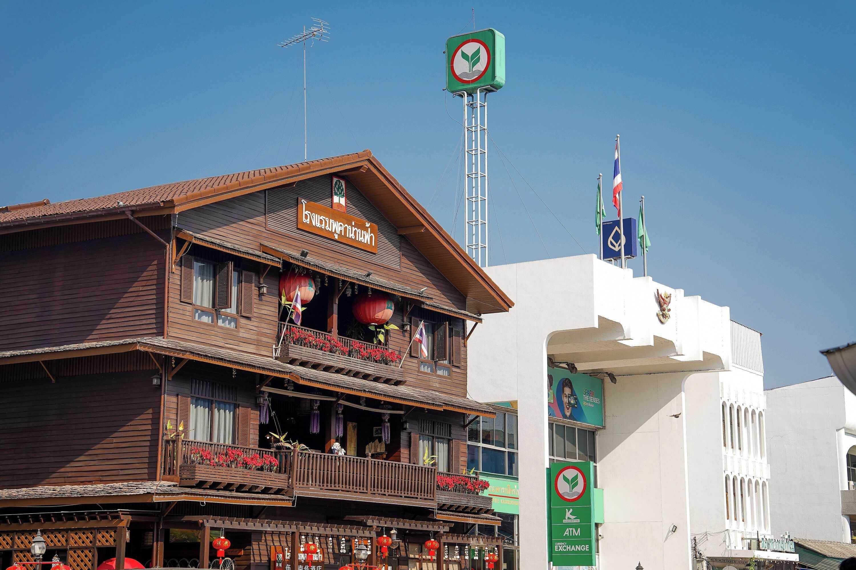 A traditional wooden building with a balcony, a sign indicating a restaurant, and a flag on top.