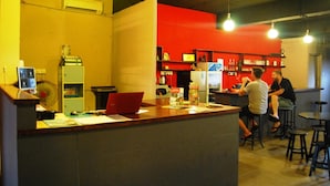 A bar area with a counter, stools, and a red wall with shelves. - Borneo Seahare Guesthouse - Hostel (Kuching)
