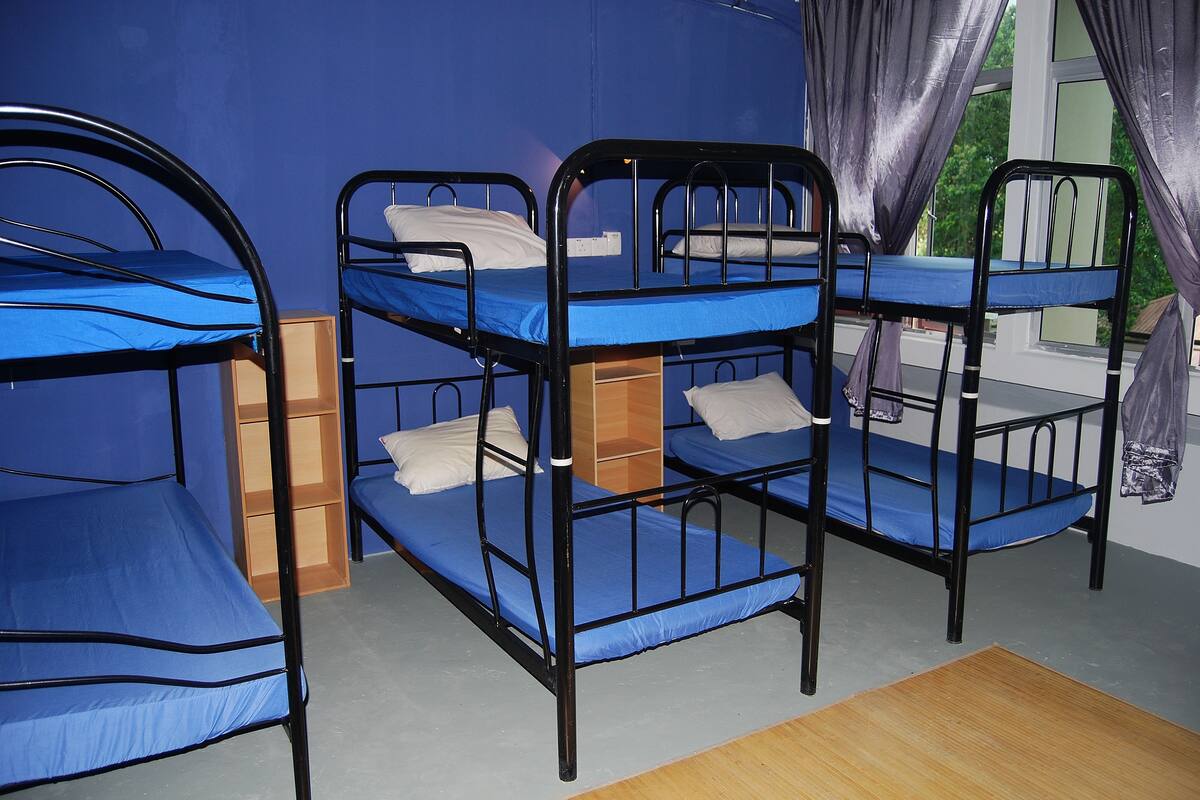 Ein Zimmer mit Etagenbetten, Holzschränken und einem Fenster mit Vorhängen.