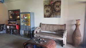 A living room with a wooden bench, a coffee table, a bookshelf, and a large vase. - Borneo Seahare Guesthouse - Hostel (Kuching)