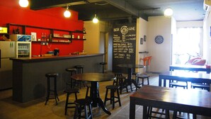A bar area with stools, tables, and a menu board listing drinks. - Borneo Seahare Guesthouse - Hostel (Kuching)