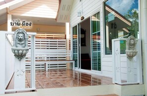 A covered outdoor area with a bench, a white fence, and a door with glass panels. - Byemuang Khaokho Resort View Talaymok (Khao Kho)