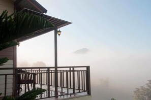 A balcony with a railing, a chair, and a potted plant. - Byemuang Khaokho Resort View Talaymok (Khao Kho)