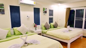 A hotel room with two beds, each with green bedding and white pillows. There is a nightstand with a lamp and a vase with flowers. - Byemuang Khaokho Resort View Talaymok (Khao Kho)