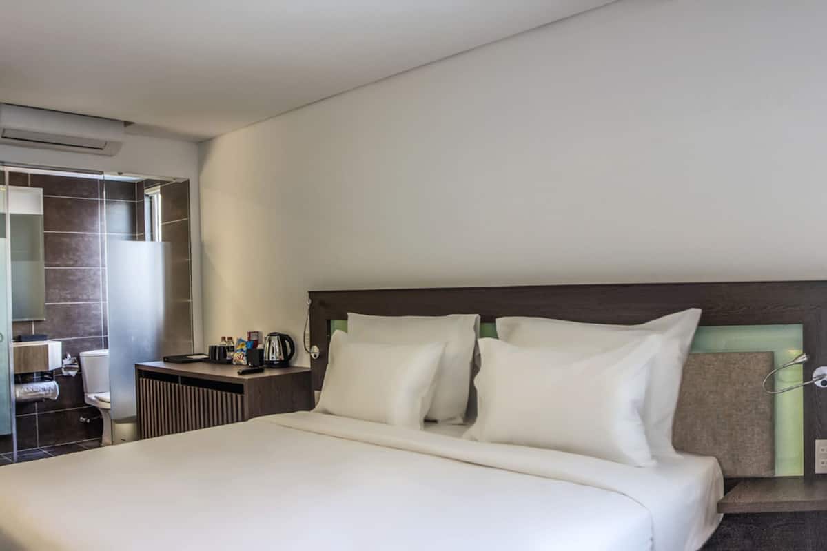 Une chambre d’hôtel avec un grand lit, un bureau et une fenêtre donnant sur la ville.