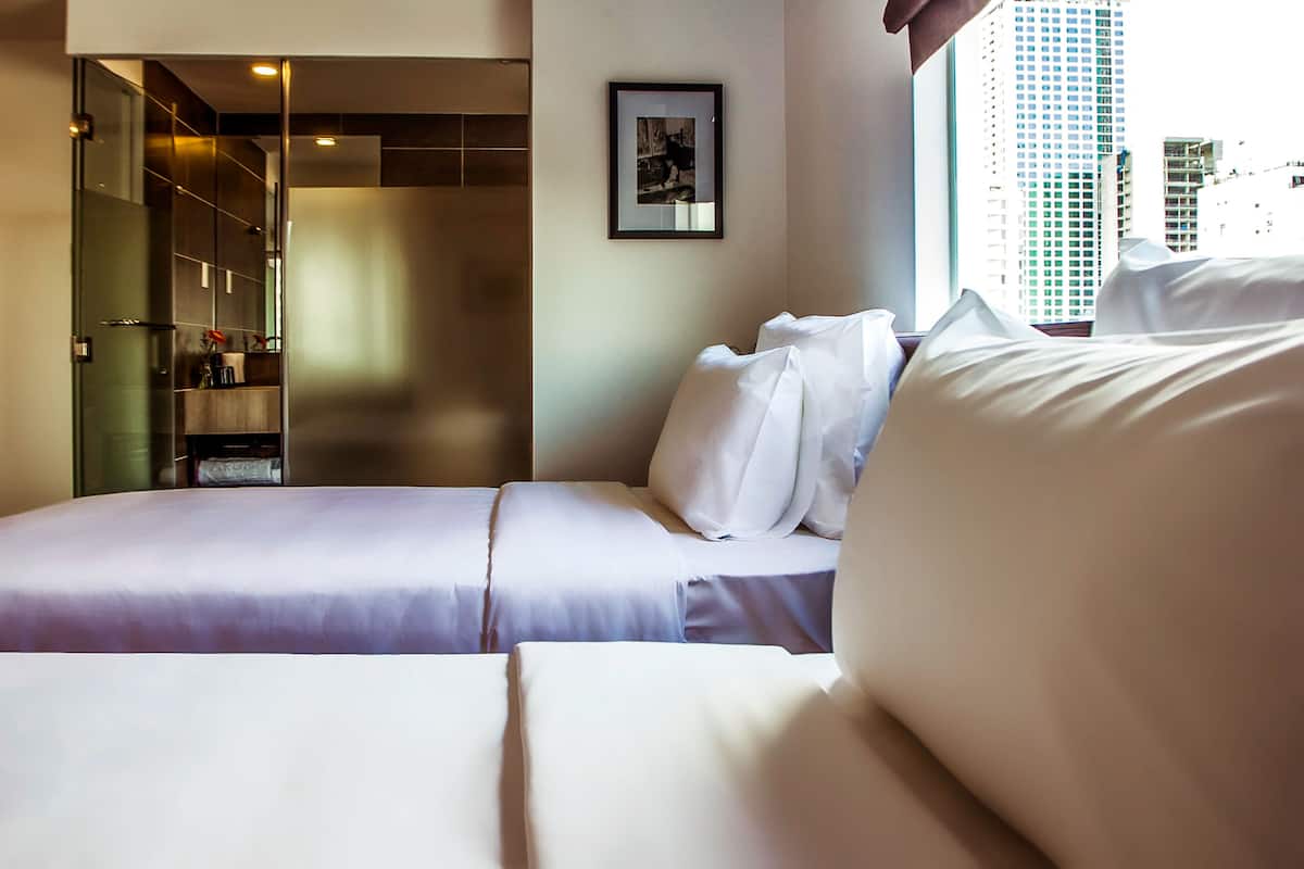 Une chambre d’hôtel avec un lit, une salle de bain dotée d’une douche à parois de verre et une vue sur la ville.