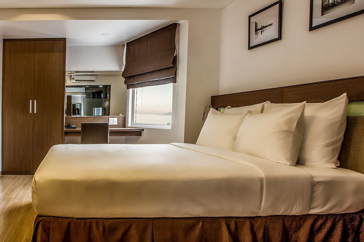 Une chambre d’hôtel avec un grand lit, un bureau et une vue sur la mer.