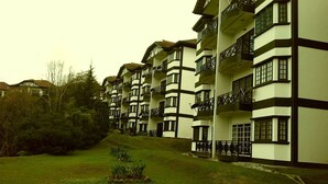 Una hilera de edificios de varios pisos con balcones, rodeados de vegetación.