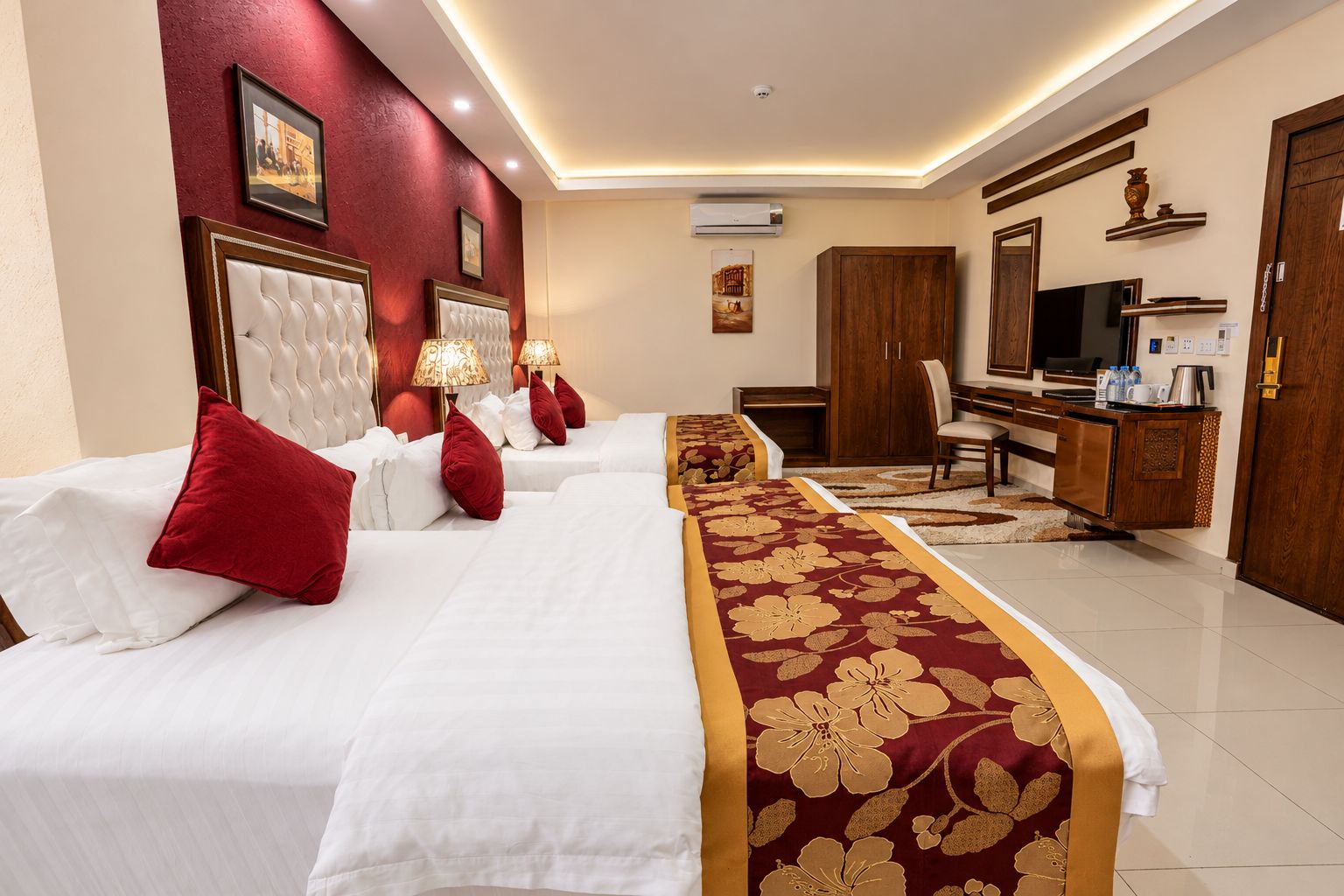 A hotel room with a large bed, a desk, a television, and a wardrobe.