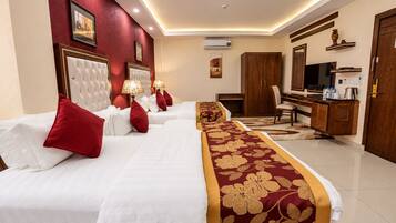A hotel room with a large bed, a desk, a television, and a wardrobe.
