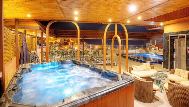 Un espace avec un jacuzzi, des sièges et une piscine.