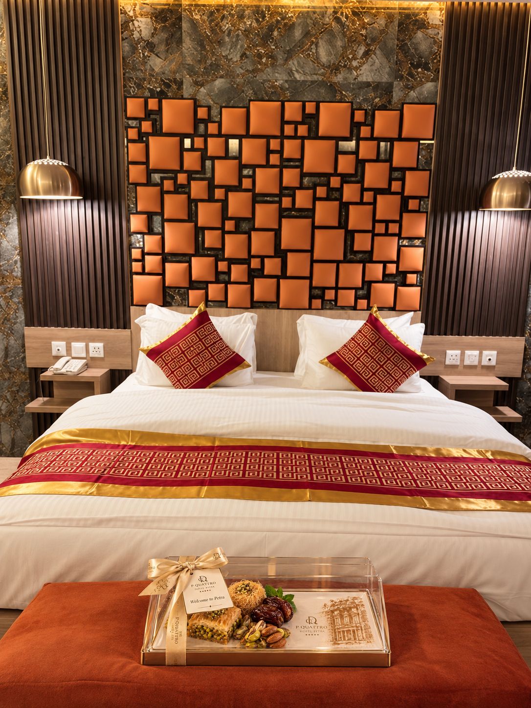 Een hotelkamer met een modern design, met een groot bed met een geborreld beddegoed, twee nachtkastjes met lampen, en een decoratief wandpaneel.