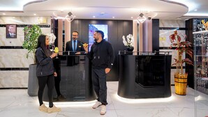 Un espace d’accueil moderne avec des murs en marbre, un comptoir d’accueil et un grand écran.