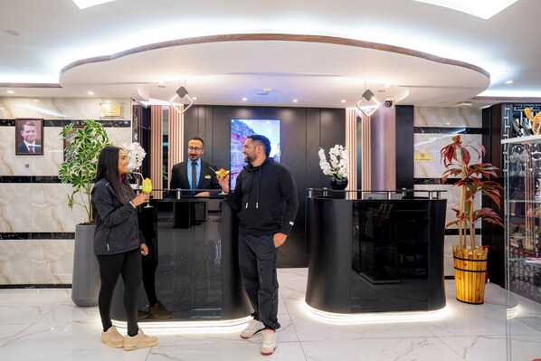 A modern reception area with marble walls, a reception desk, and a large screen. - P Quattro Relax Hotel (Wadi Musa)